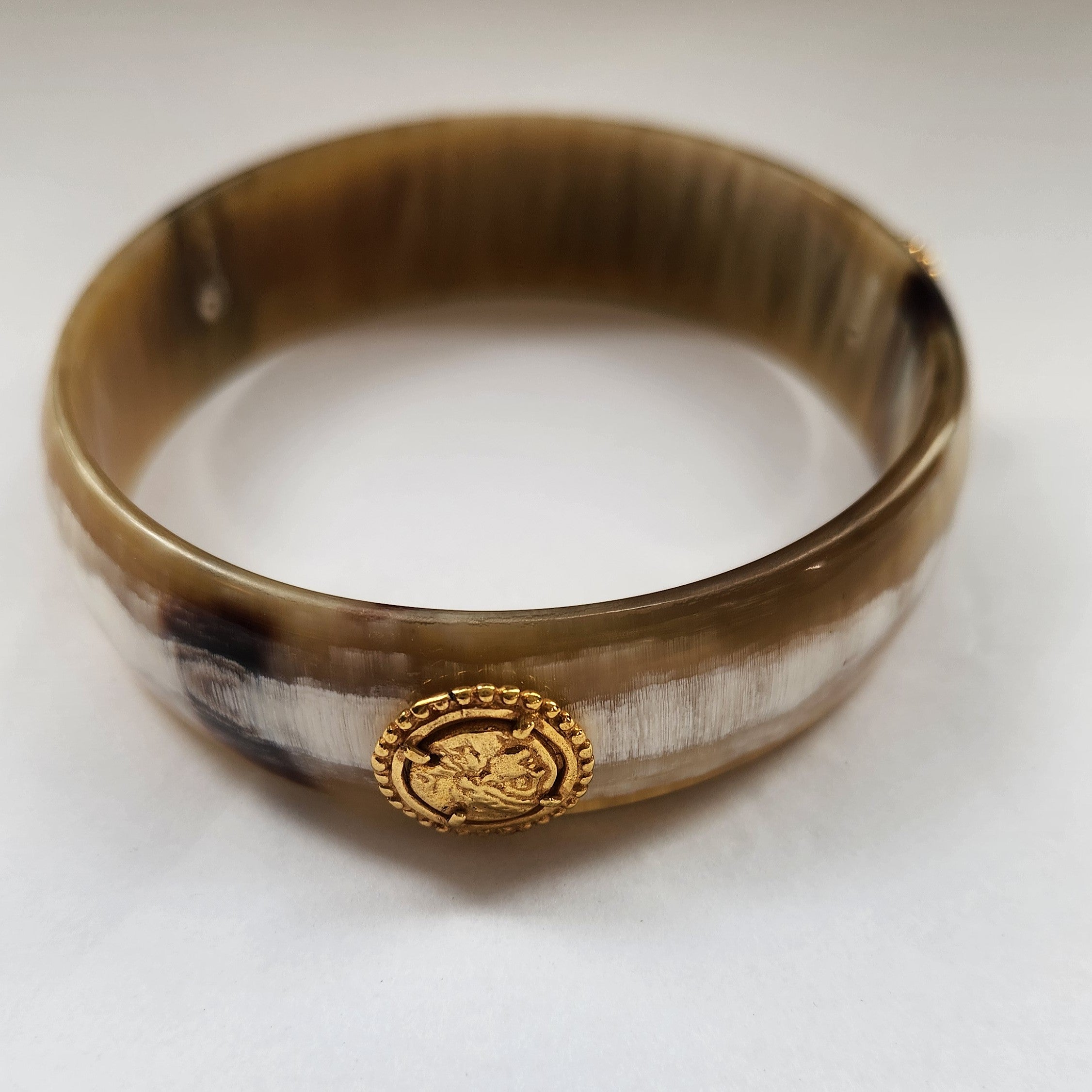 Horn bracelet with a gold emblem on a light background