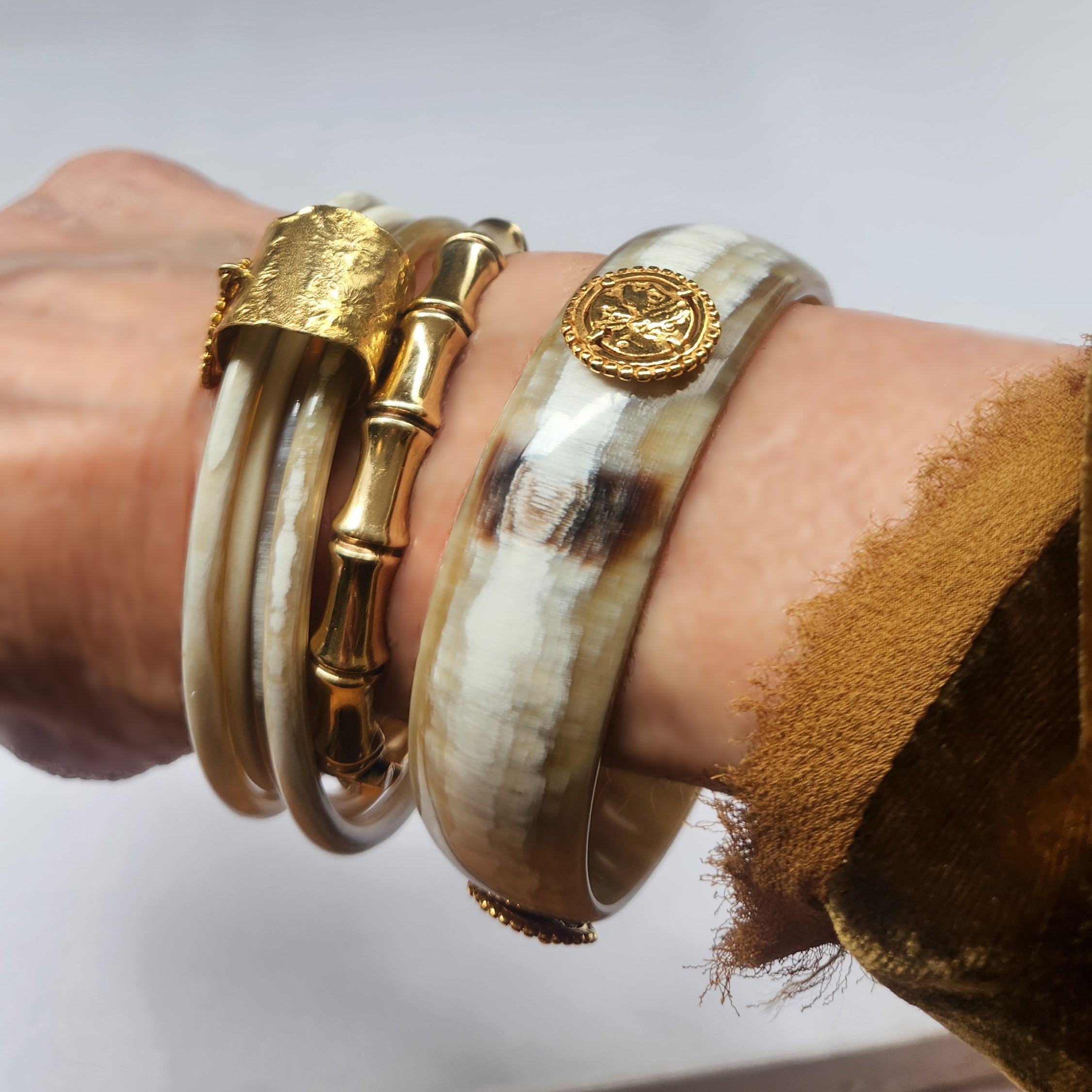 Horn bracelet with a gold emblem on a light background
