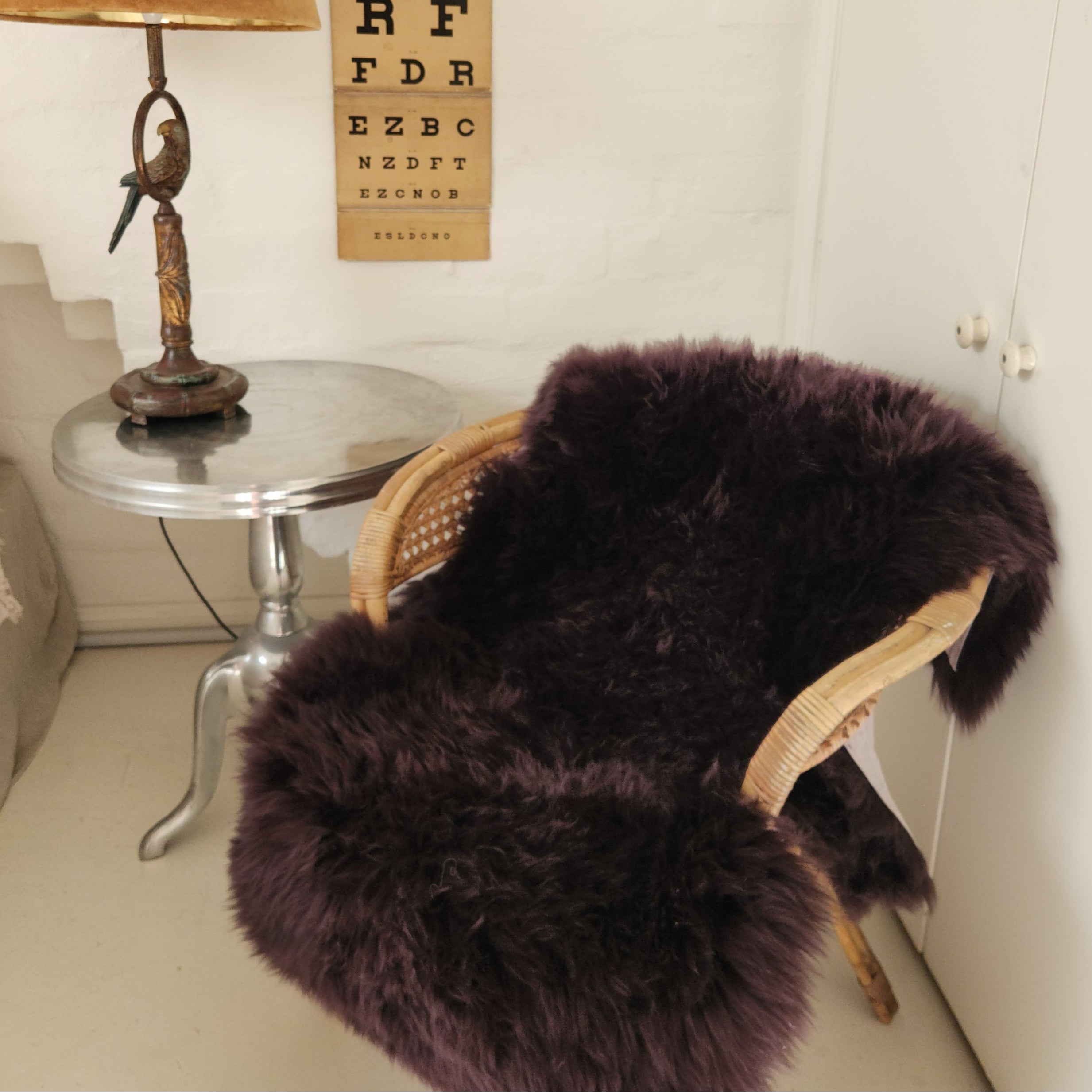 Aubergine coloured merino sheepskin draped over a chair
