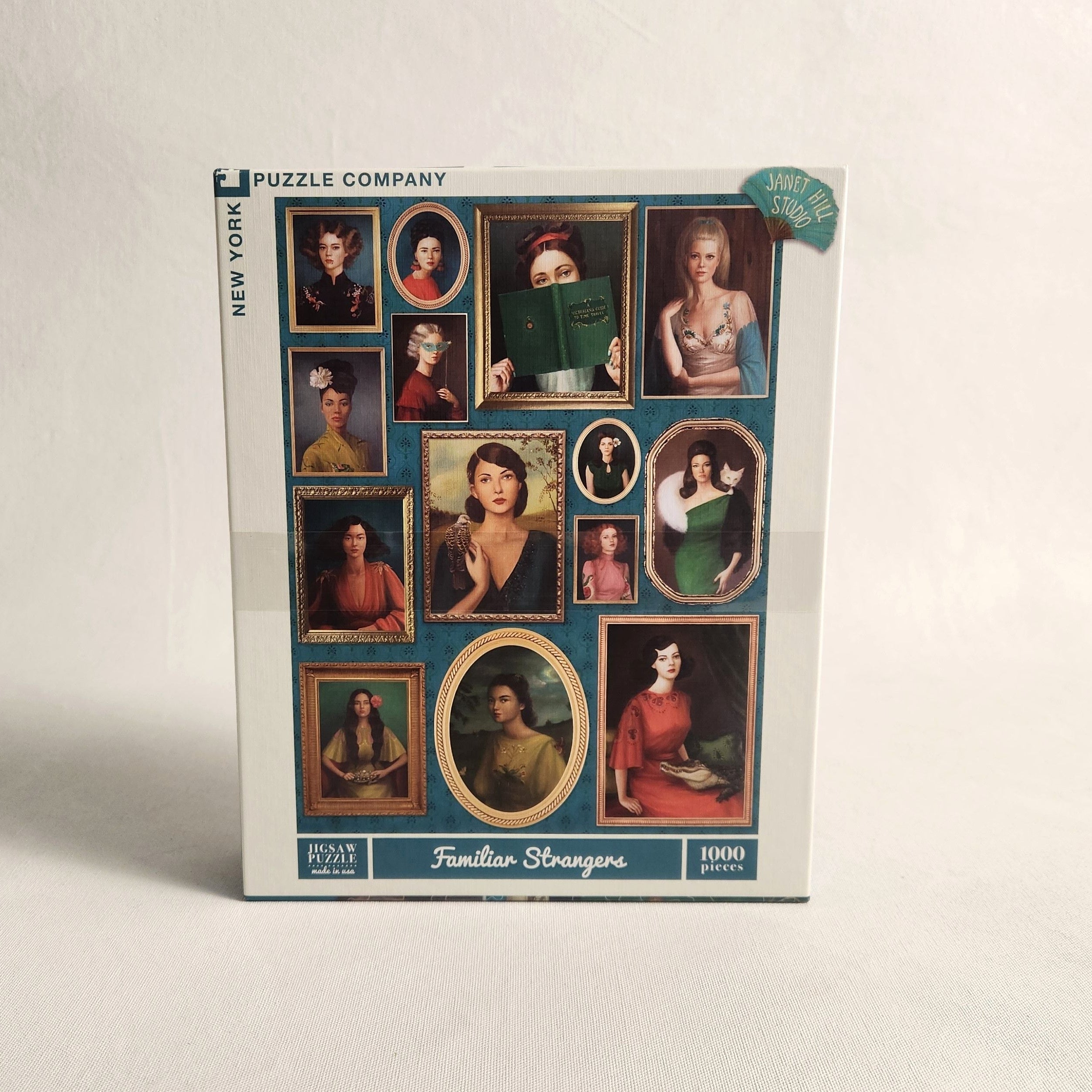 A 1000-piece jigsaw puzzle box by Puzzle Company titled 'Familiar Strangers' featuring a collage of vintage portrait paintings, photographed on a light neutral background.