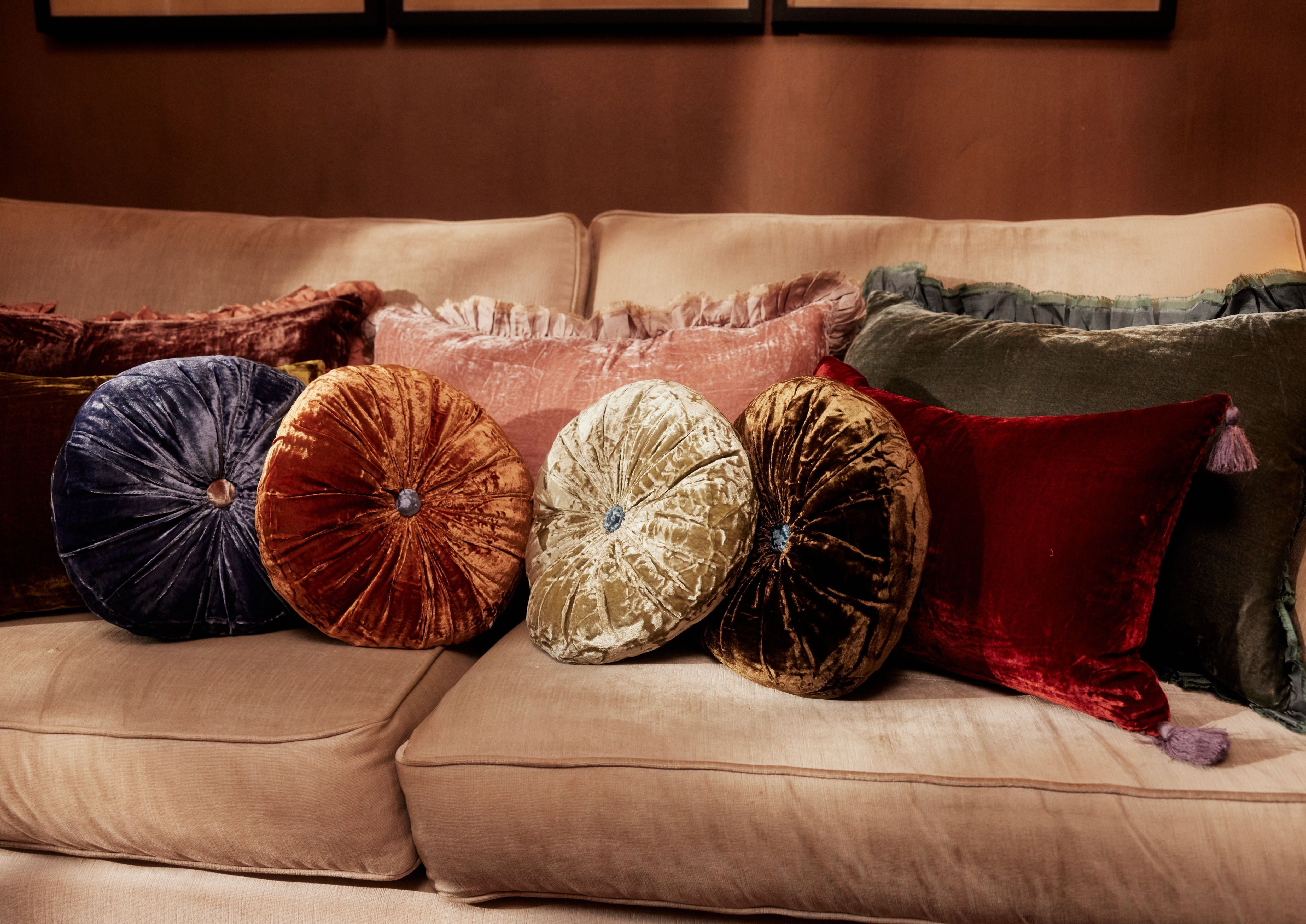 Round silk velvet cushions with contrasting buttons, displayed on a sofa.