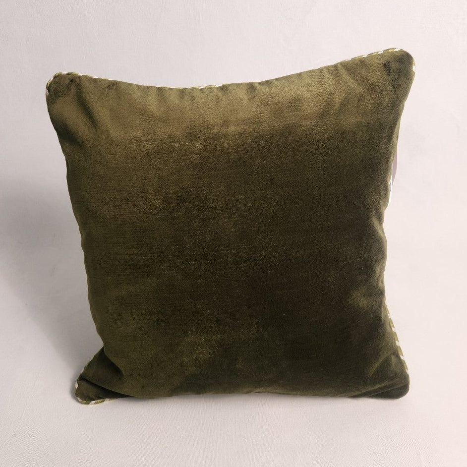 An olive green velvet square throw pillow with gold piping along the edges, photographed against a plain off-white background.