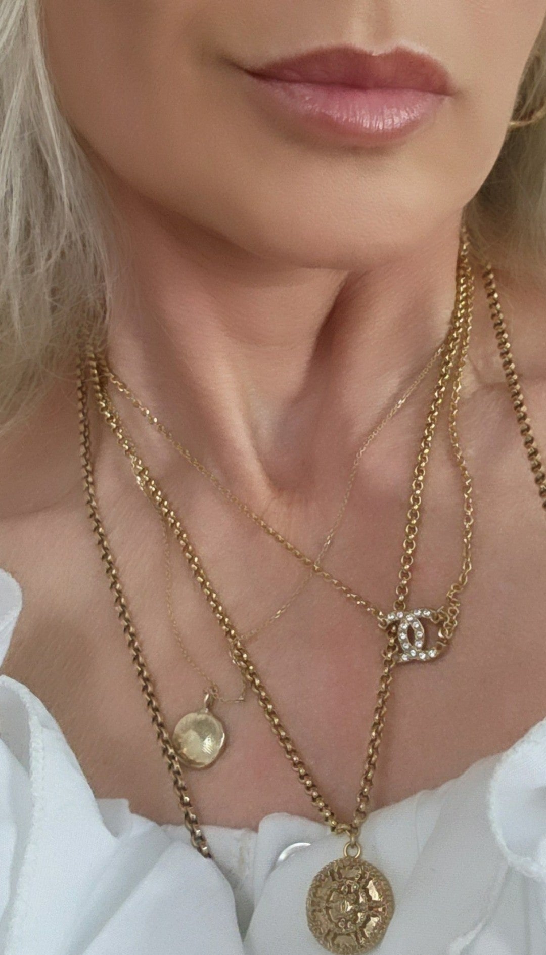 Close-up of a woman wearing gold necklaces with a white blouse.