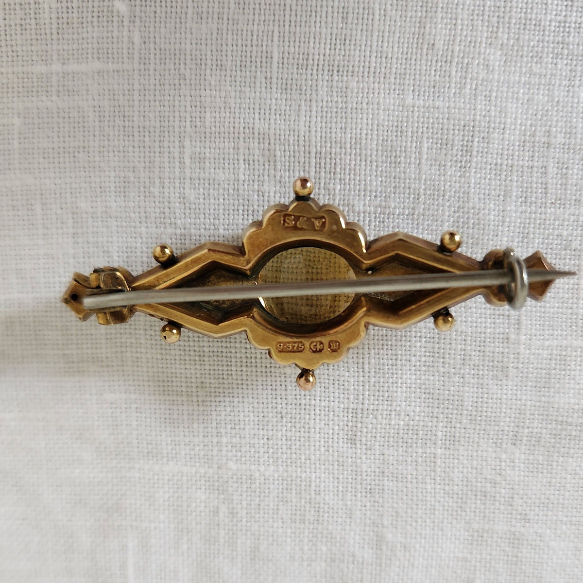 The back of a Antique Citrine Brooch on linen fabric background