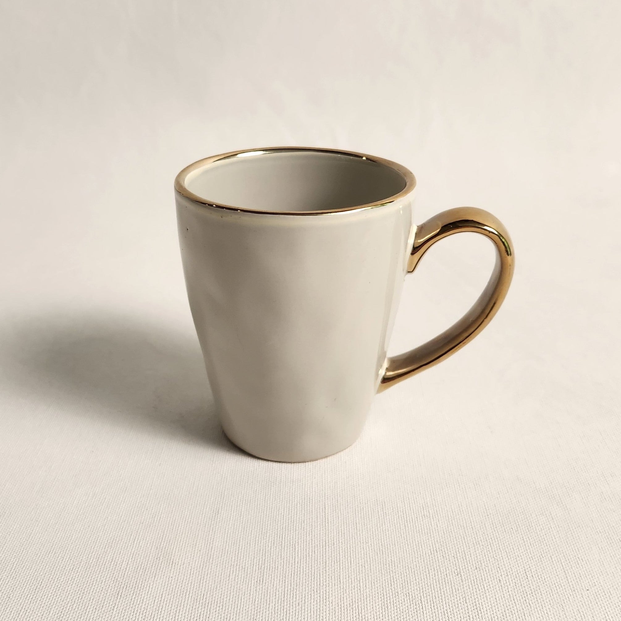 French Grey mug with gold rim and handle on a beige background