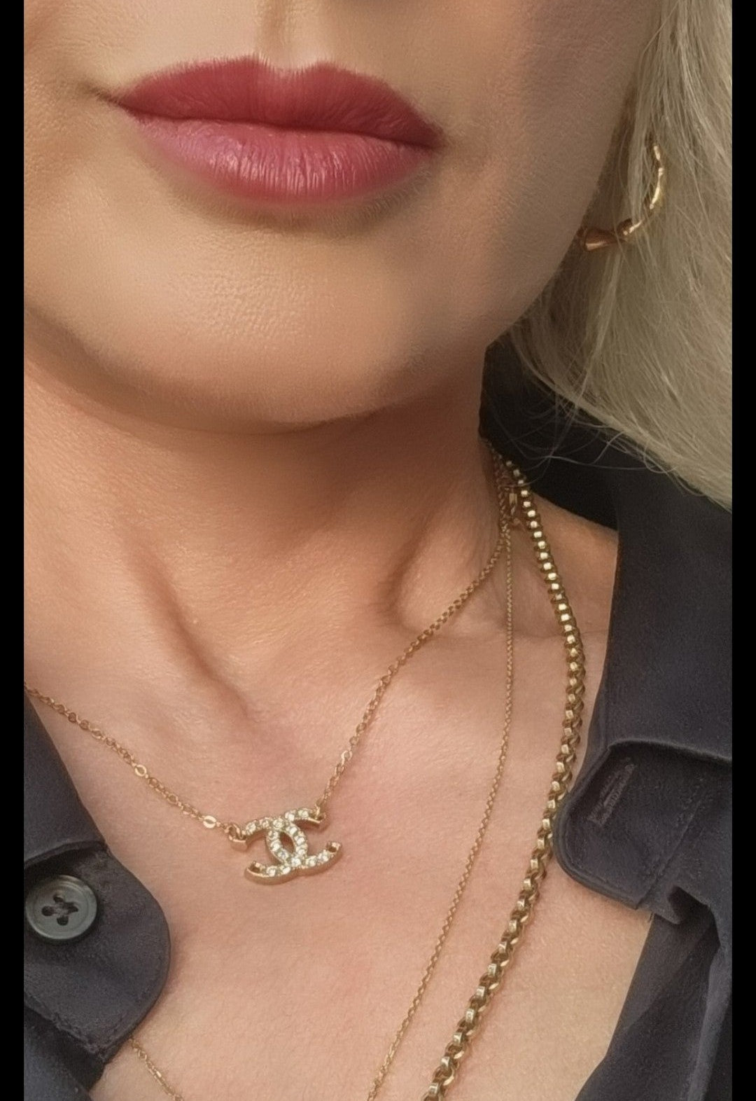 Close-up of a person wearing a gold necklace with a Chanel logo 
